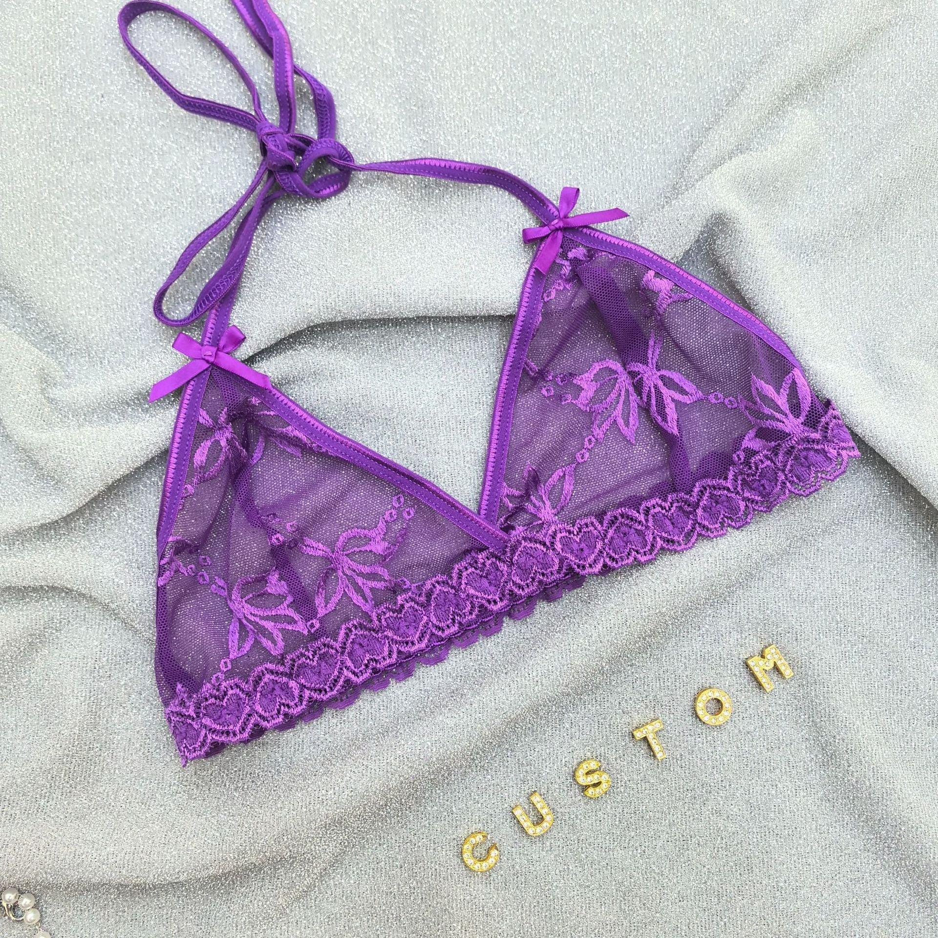 Purple sheer lace bralette with floral embroidery, adjustable tie straps, on silver fabric background.