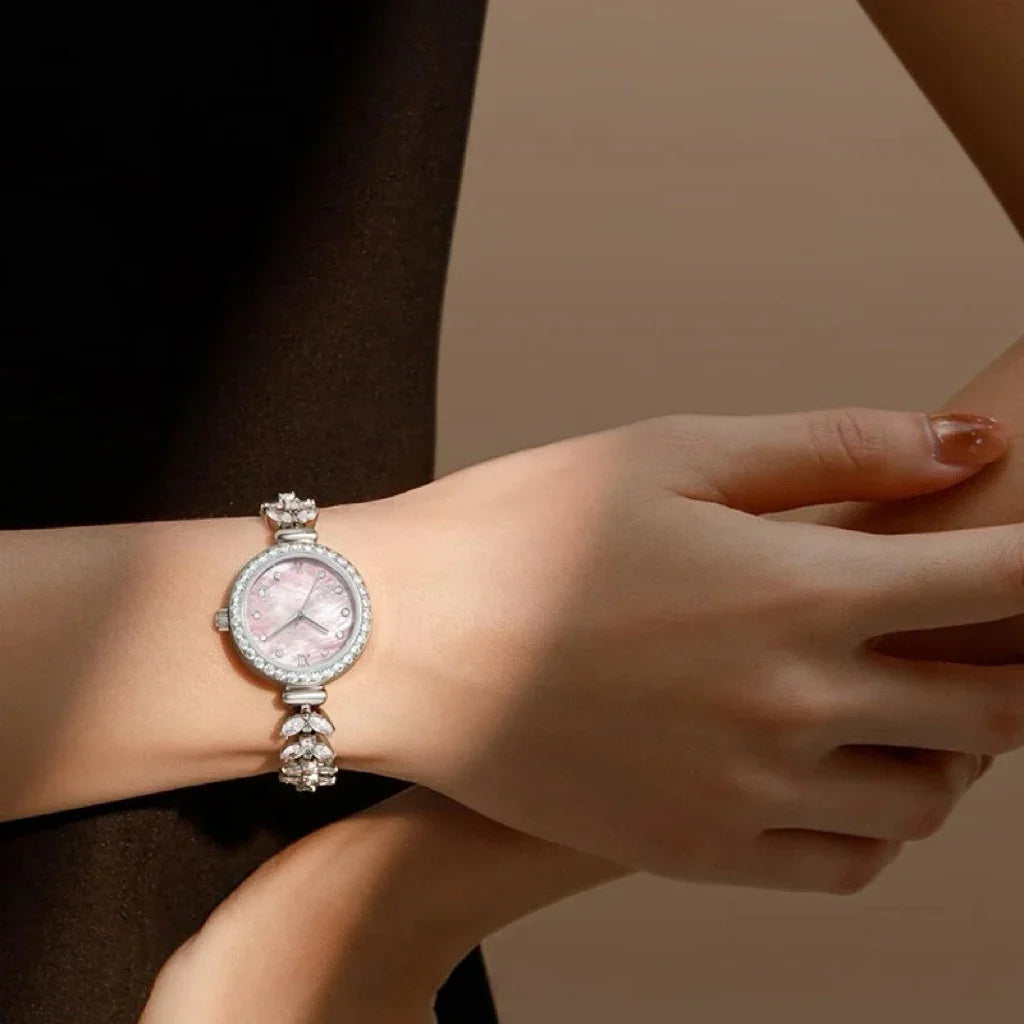 Elegant silver wristwatch with pink face, crystal accents, and slim fitted design