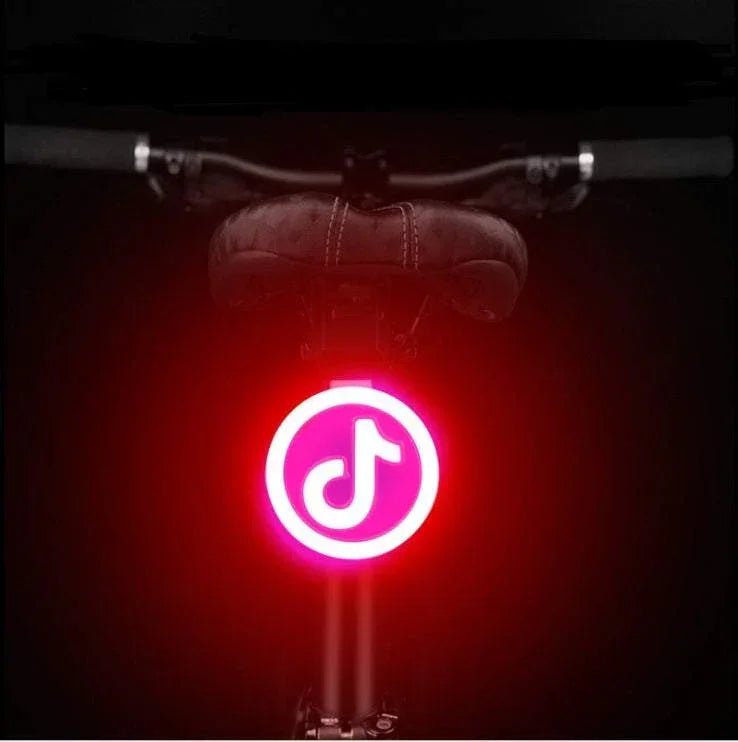 Bicycle seat with glowing red LED round tail light and musical note symbol, night setting