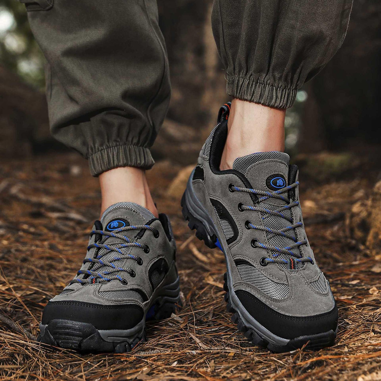 Gray suede and mesh hiking sneakers with blue accents, chunky sole, relaxed fit joggers outdoors