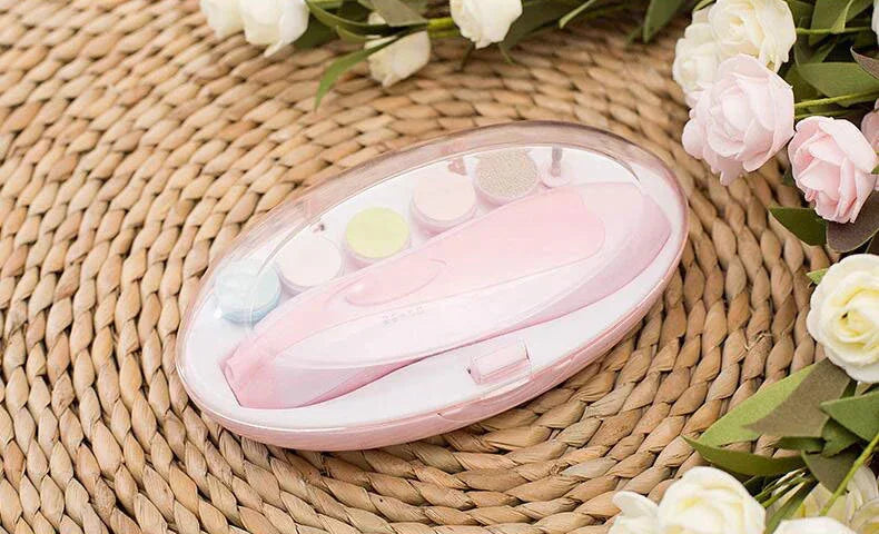 Pink nail care kit with multiple attachments in a clear plastic case on woven mat with flowers