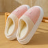 Pink and cream slip-on indoor slippers with ribbed fabric and plush lining on a wooden floor
