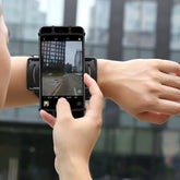 Black smartphone armband, adjustable fit, worn on forearm, street setting