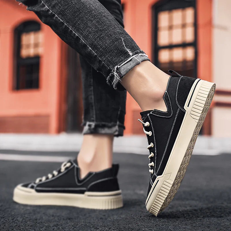 Black canvas low-top sneakers with white soles, worn with distressed slim-fit jeans