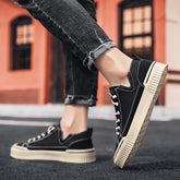 Black canvas low-top sneakers with white soles, worn with distressed slim-fit jeans