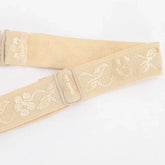 Beige adjustable strap with floral embroidery and metal buckle, soft woven material