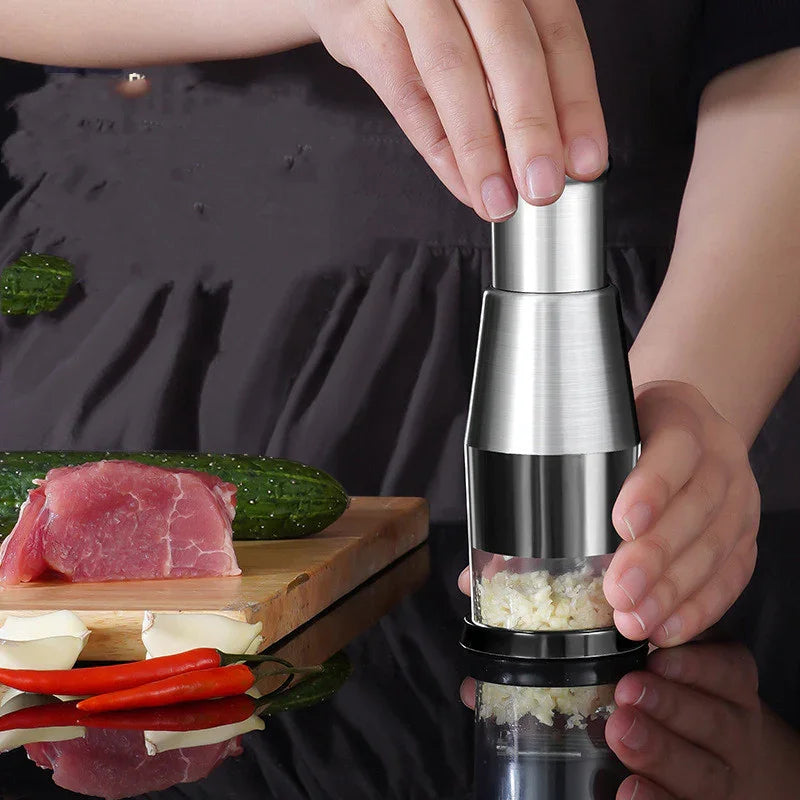 Hands using a stainless steel garlic chopper with chopped garlic in a kitchen setting