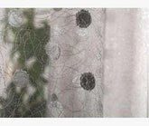 Close-up of sheer mesh fabric with black polka dots and intricate stitching detail