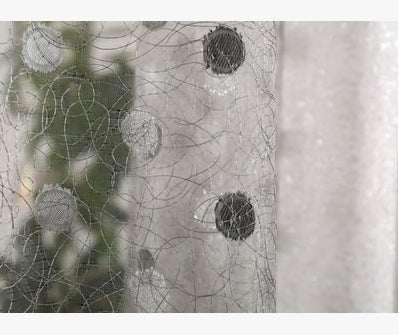 Close-up of sheer mesh fabric with black polka dots and intricate stitching detail