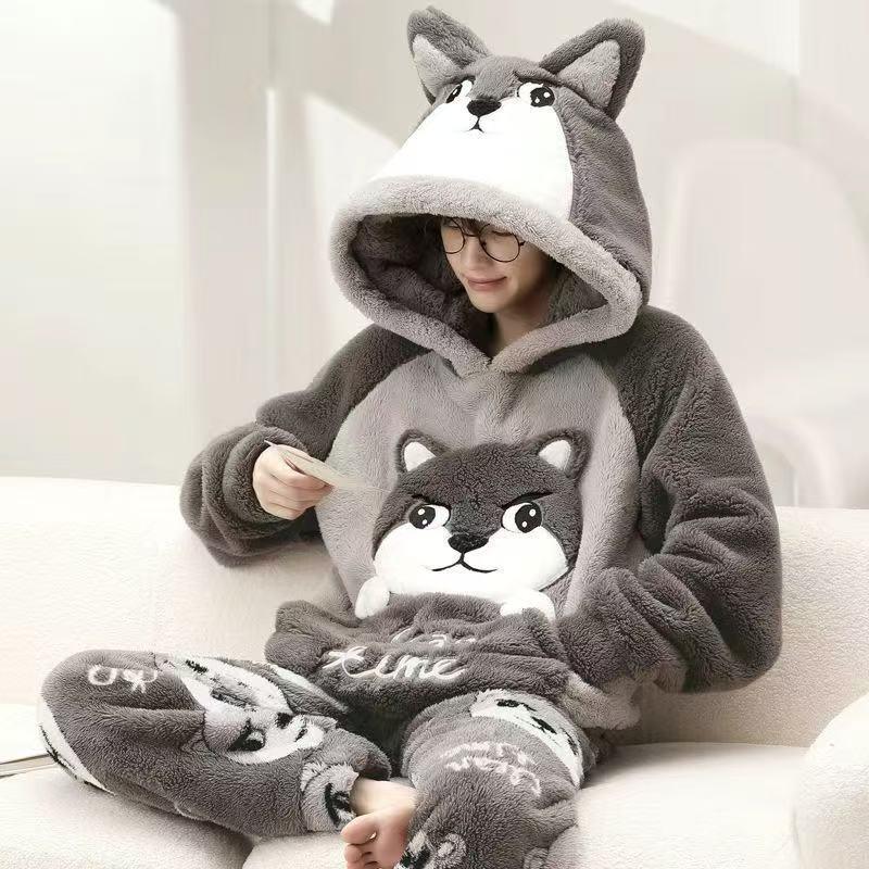 Person wearing grey plush wolf pajama set with hood, animal ears, and relaxed fit on sofa