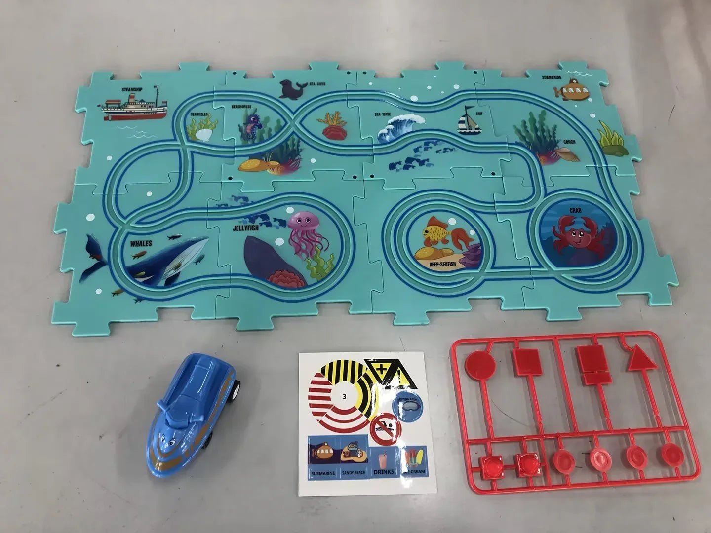 Blue ocean-themed puzzle play mat with illustrated sea animals, plastic toy car, and red sign accessories