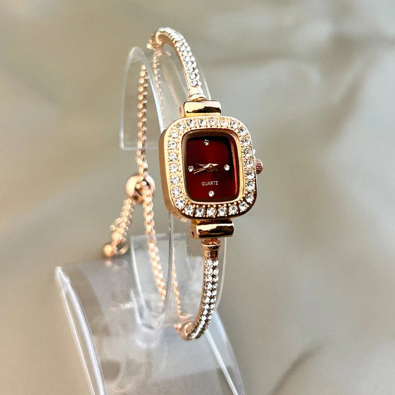 Gold-tone bracelet watch with crystal accents, red square dial, and slim adjustable fit