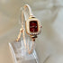 Gold-tone bracelet watch with crystal accents, red square dial, and slim adjustable fit
