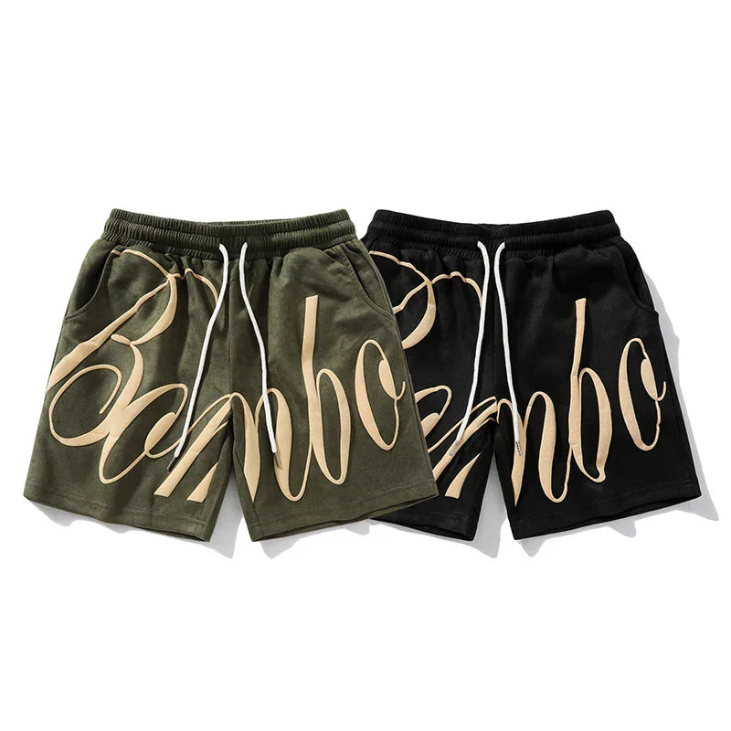 Streetwear shorts in olive green and black with bold beige script, relaxed fit, drawstring waist