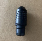 Black ribbed plastic connector piece on a plain brown background