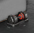 Adjustable black and red dumbbell with weight markings, compact fit under gray sofa