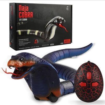 Realistic remote control snake toy with lifelike cobra design, black and blue scales, red tongue, and wireless controller, with product packaging in the background.