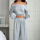 Woman wearing a light gray off-shoulder long sleeve top and matching wide-leg lounge pants