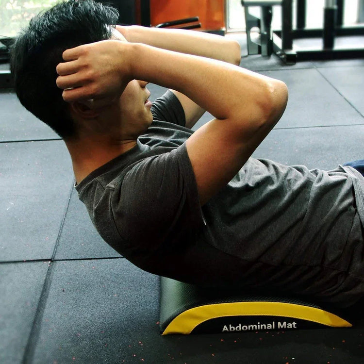 Man in a fitted dark gray short sleeve t-shirt doing crunches on an abdominal mat at the gym