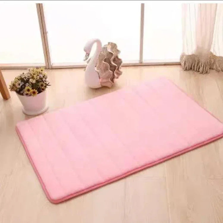 Soft pink rectangular mat with a plush texture on light wood floor near a window and decor.
