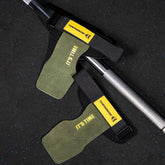 Olive green suede lifting straps with black and yellow accents, adjustable fit, on gym floor.