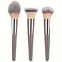 Set of three makeup brushes with soft bristles and metallic gray handles, modern design