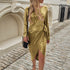 Woman in gold metallic wrap dress with long sleeves and midi fit, walking on stone path