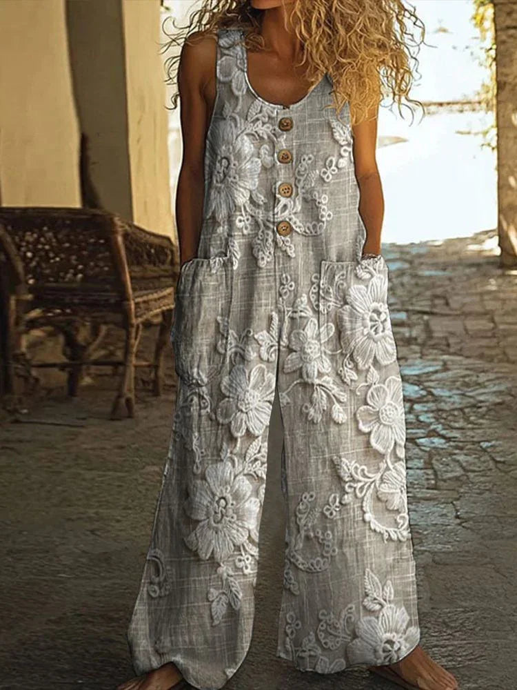 Woman wearing loose-fit grey linen jumpsuit with white floral embroidery, front buttons, and pockets