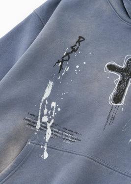 Blue streetwear hoodie with abstract paint splatter, cross graphic, and relaxed fit
