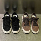 Two pairs of low-top suede sneakers in black and brown with chunky laces and white soles