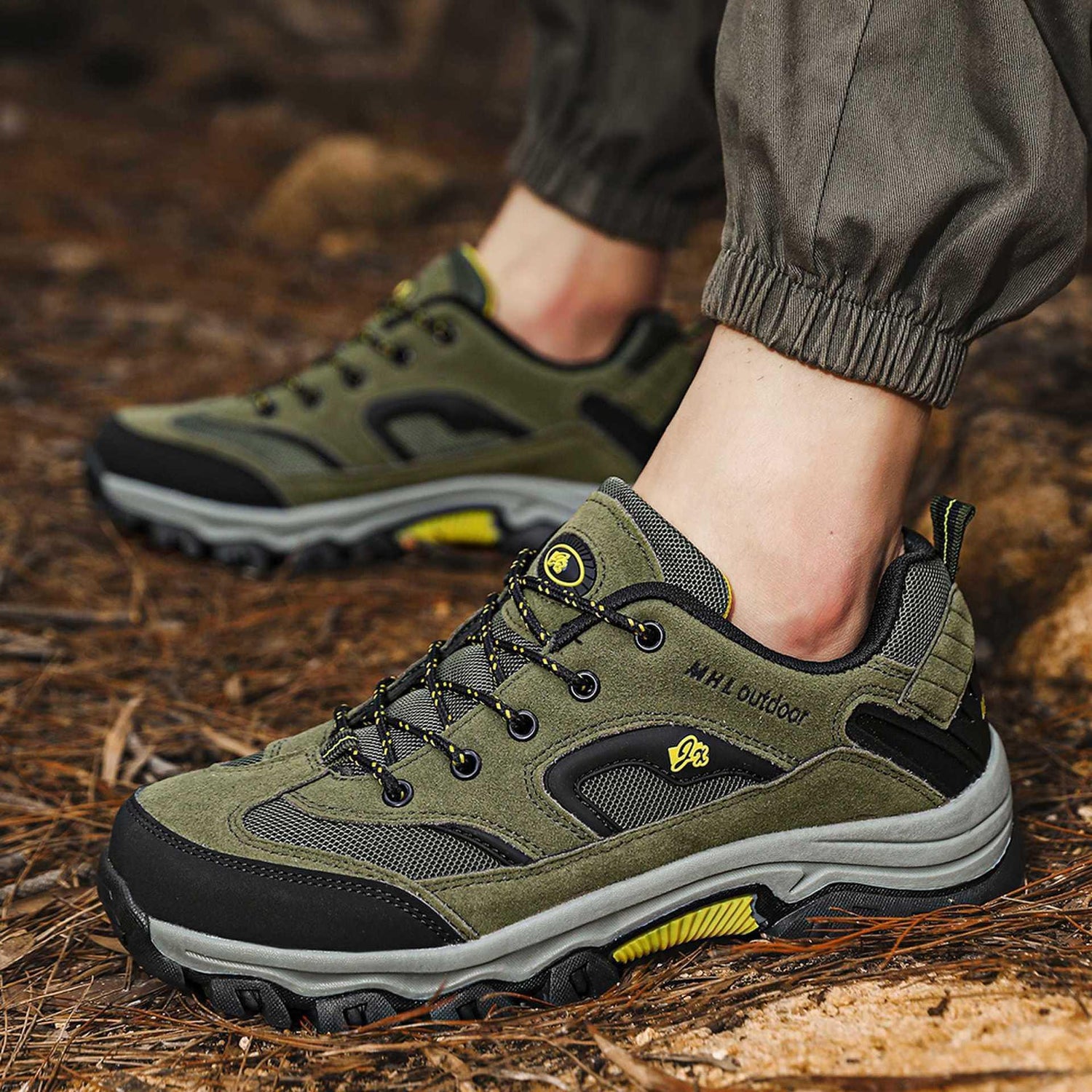 Olive green outdoor sneakers with black mesh panels, rugged sole, and lace-up closure on forest floor