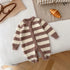 Brown and cream striped fuzzy knit baby romper with front buttons, laid flat on a bed