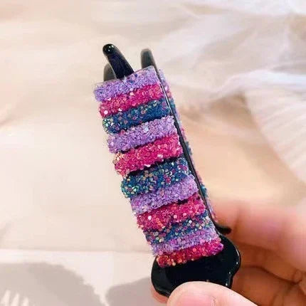 Colorful textured hair clip in pink, purple, and blue, chunky knit fabric style, close-up