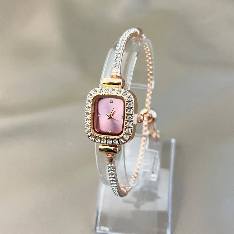 Rose gold square watch with pink dial, crystal accents, and slim bracelet strap