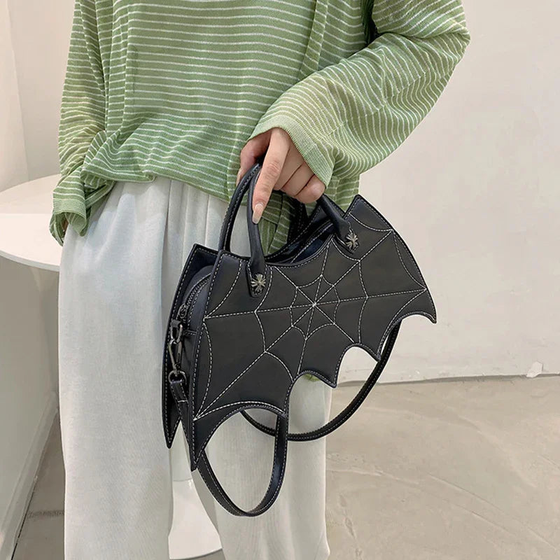 Green striped oversized top with loose white pants, holding black bat-shaped handbag with web detail.