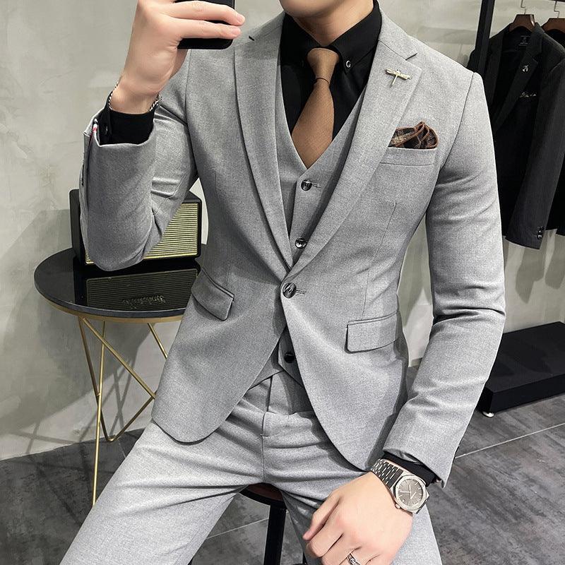 Man wearing a slim fit light gray suit with matching vest, black shirt, and brown tie