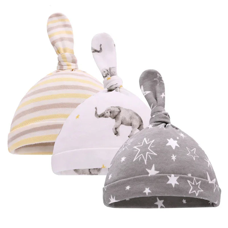 Three soft cotton baby hats with knotted tops, featuring stripes, animal, and star prints.