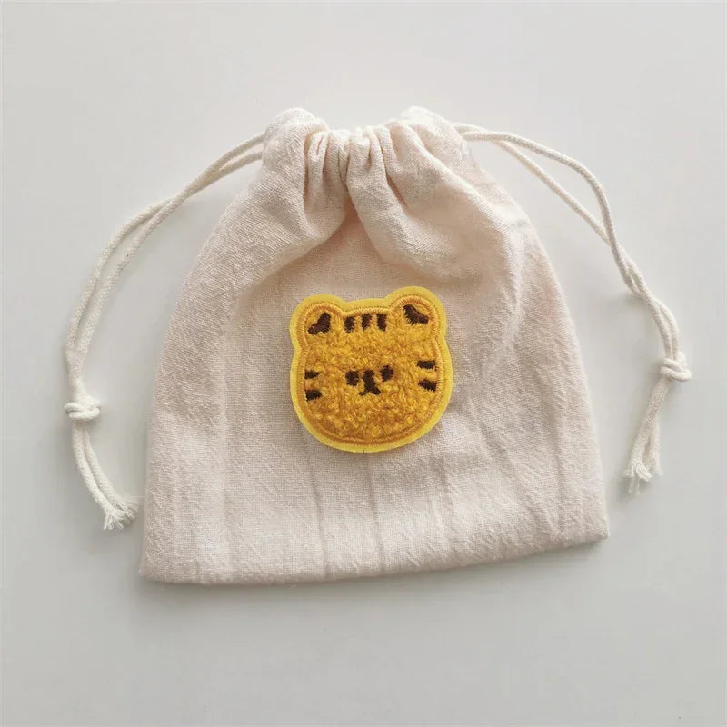 Beige cotton drawstring pouch with yellow embroidered animal patch, casual streetwear accessory.
