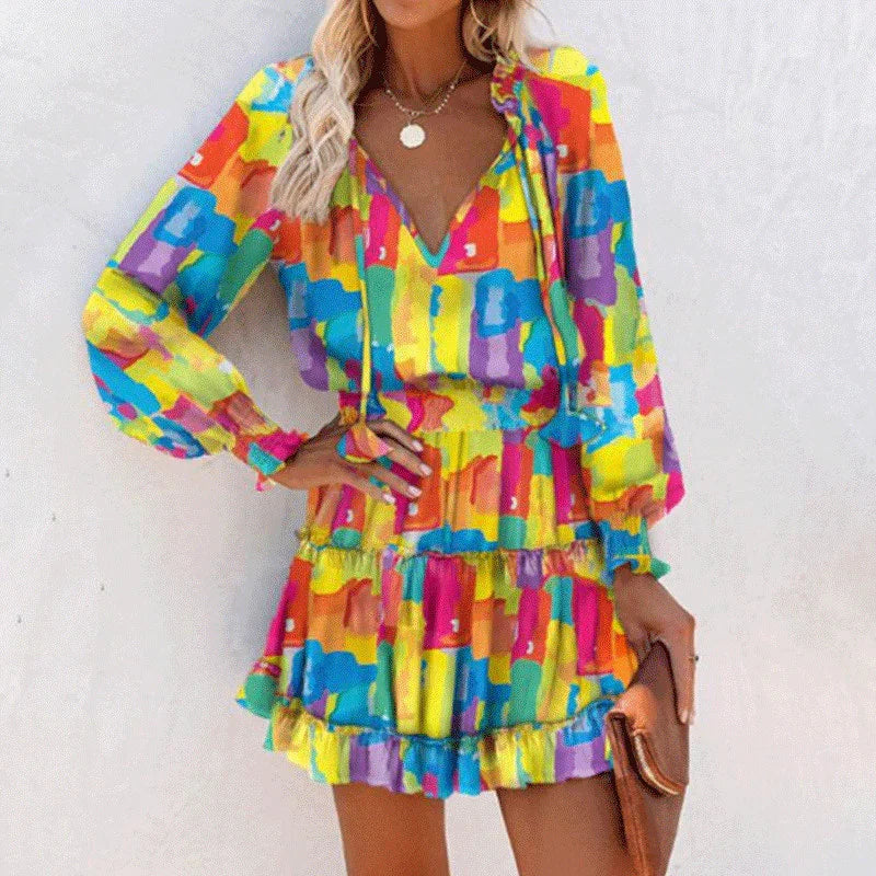 Woman wearing a colorful abstract print mini dress with long sleeves and a ruffled hem
