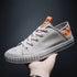 Gray canvas low-top sneaker with rubber sole and orange accent tags, casual streetwear style