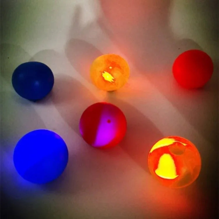 Colorful glowing bouncy balls on white surface, made of soft translucent plastic.