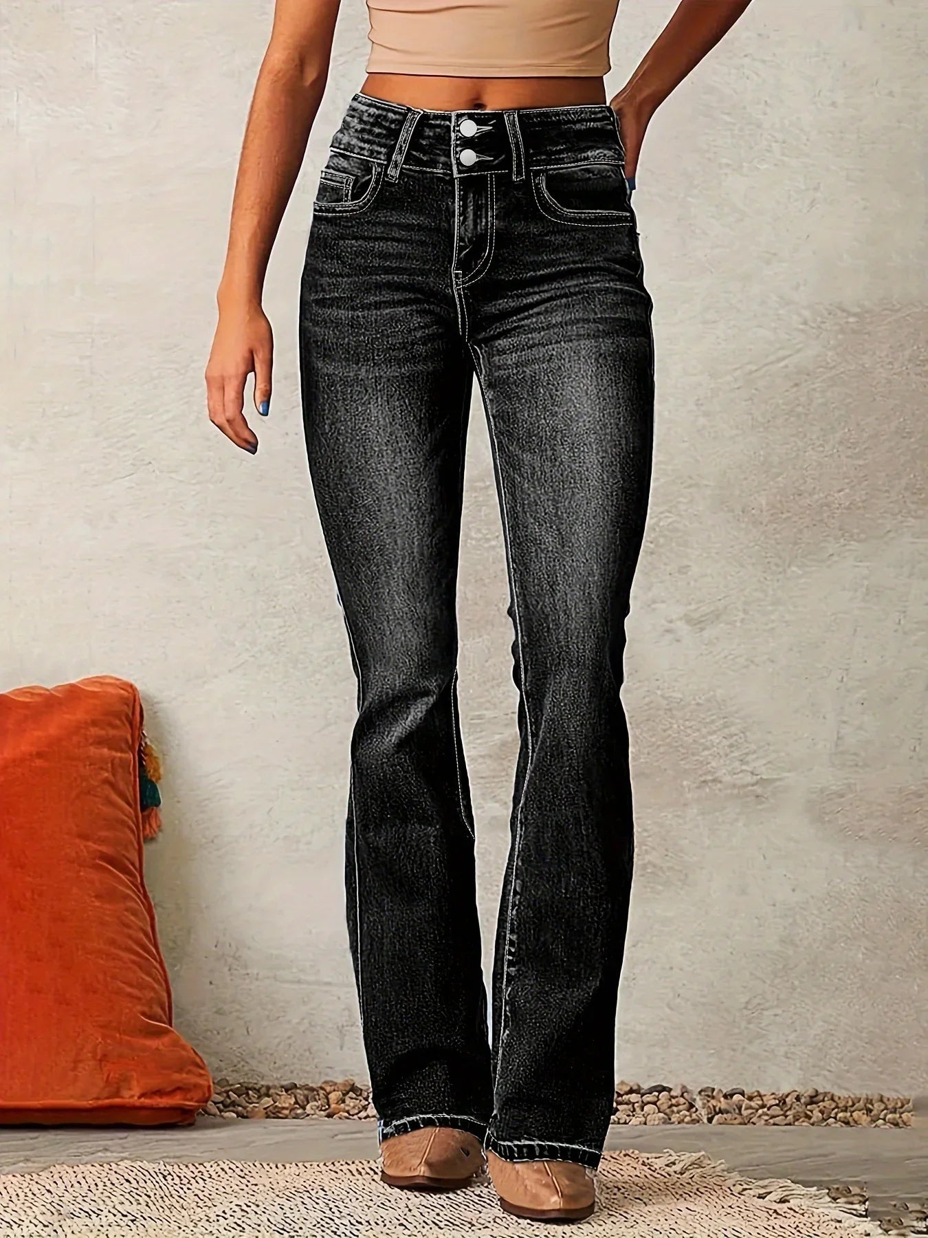 Woman wearing high-waisted black flared jeans with double button closure and white stitching