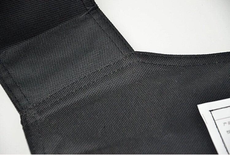 Close-up of black textured fabric vest with reinforced stitching, rectangular cut, relaxed fit
