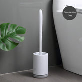Modern gray floor-standing toilet brush set with sleek white handle beside toilet