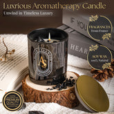 Black scented candle for men with obsidian crystals and teakwood scent in luxury glass jar with gold lid on wooden coaster
