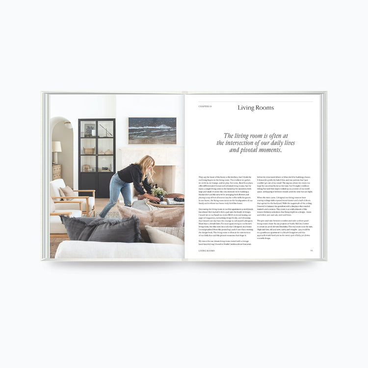 The Art of Home book open to living room design page with woman styling a sofa and modern interior decor by Shea McGee