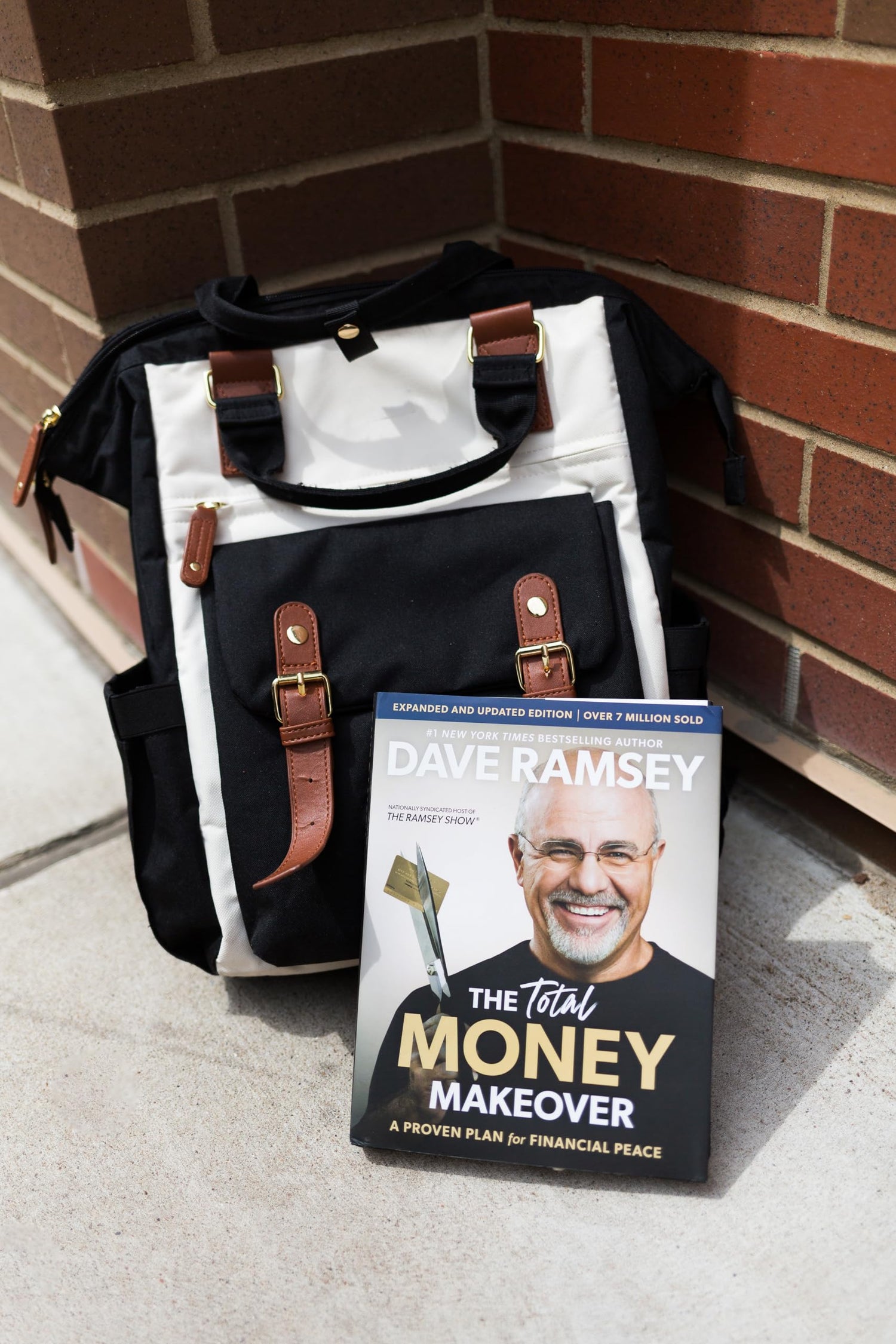 The Total Money Makeover hardcover book by Dave Ramsey with black and white bag background
