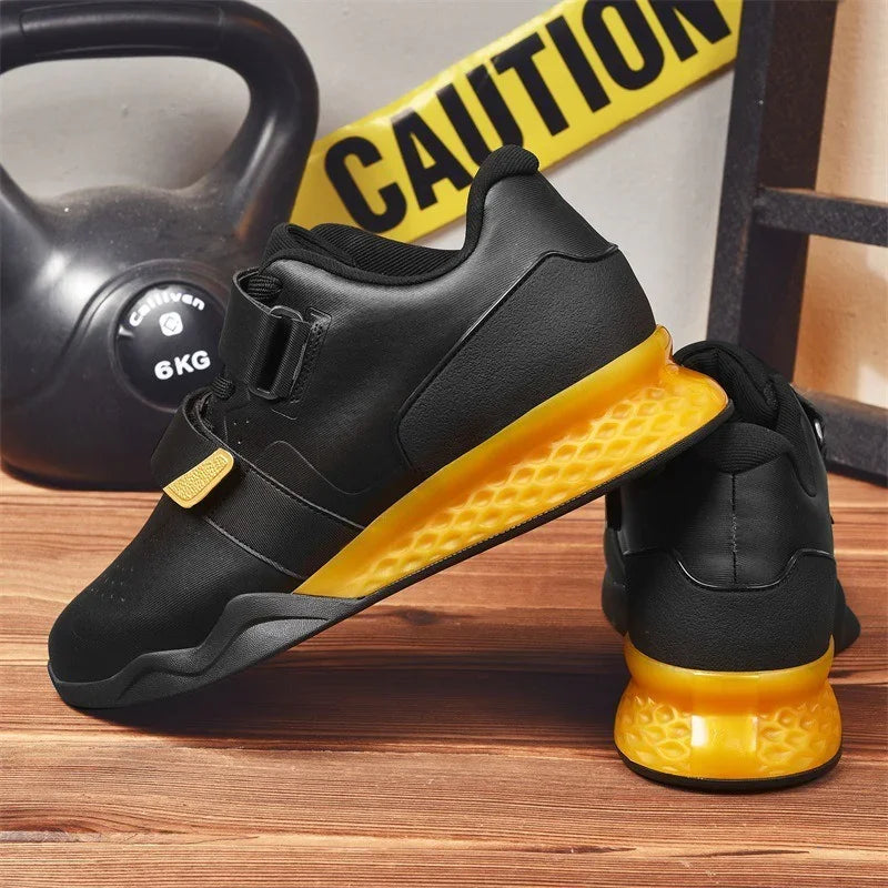 Black athletic sneakers with yellow textured soles, low-top fit, on wood floor.
