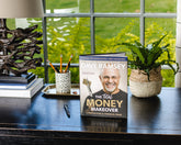 The Total Money Makeover book by Dave Ramsey on desk with plant and pencils, financial planning guide hardcover edition