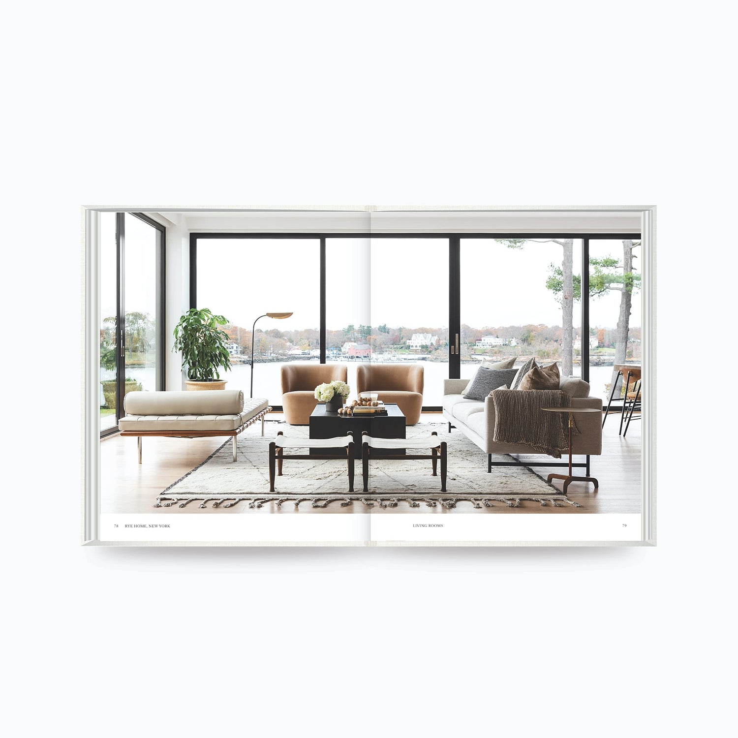 Open book showing modern living room design with large windows and neutral furniture from The Art of Home by Shea McGee